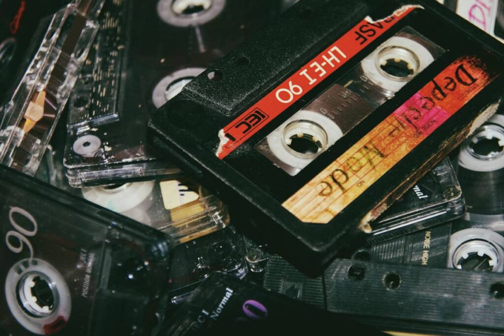 A close-up of various cassette tapes piled together, showcasing their labels, colors, and vintage textures.